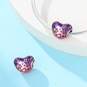 Dettaglio del charm a forma di cuore con smalto sfumato rosa e scritte Love incise a mano
