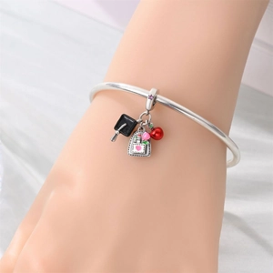 Silver bracelet with graduation charms featuring a black cap, backpack, and red apple