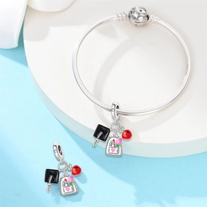 Detailed view of graduation charm bracelet with owl cap, backpack and red apple charms