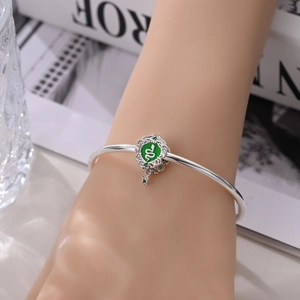 Detailopname van verzilverde slangenarmband met groen emaille en sterrenhangertje