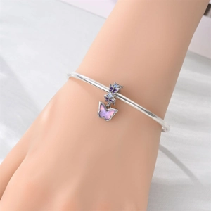 Dettaglio ravvicinato di un bracciale argento con ciondolo a farfalla sfumato viola
