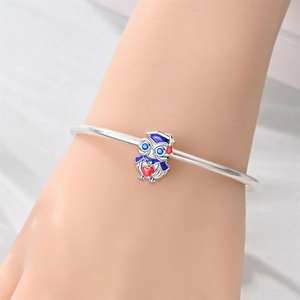 Silver owl charm with blue graduation cap and red heart detail on a metal bracelet