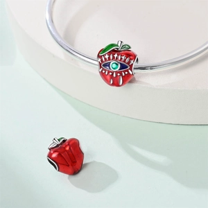 Macro-opname van rode emaille appelbedel met boze oog detail op zilveren armband
