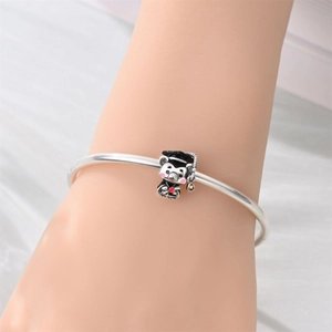 Close-up of silver graduation bear charm with black mortarboard on an open bangle