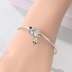Close-up of silver-plated owl bracelet with colorful gems and a floral charm on wrist
