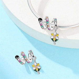 Macro detail of pencil charm with colorful zircons and enamel flower on silver chain