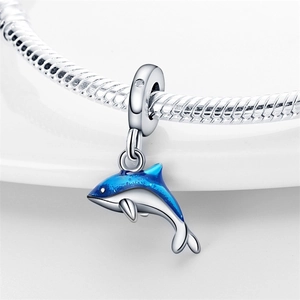 Macro detail of silver dolphin charm with blue enamel on a snake chain bracelet