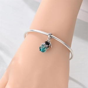 Detail of silver owl charm with teal glass bead on bracelet showing intricate textures