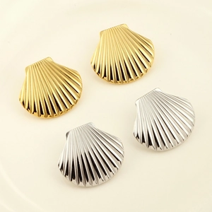Dettaglio degli orecchini a conchiglia color oro e argento su un vassoio di ceramica