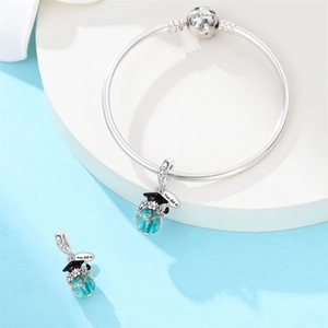 Macro detail of silver owl graduation charm with blue glass bead and engraved metal tags