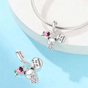 Dettaglio macro del ciondolo orso in argento con pietra rosa e medaglietta incisa regalo