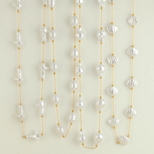 Detalle de cadena de acero dorado con perlas de agua dulce barrocas y en forma de concha