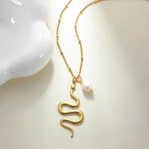 Macro shot of golden snake pendant with white baroque pearl on a fine satellite chain