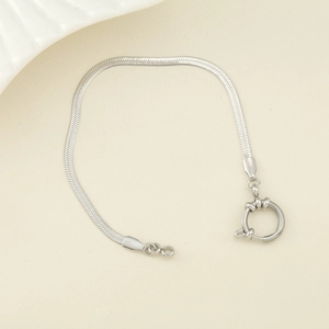 Gros plan d'un bracelet plat à maille serpent argentée avec un grand fermoir à ressort