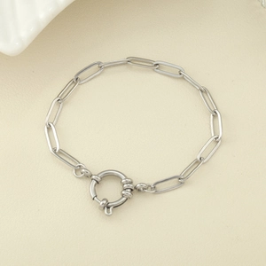 Bracelet à maillons trombones en argent avec grand fermoir à ressort sur fond beige clair