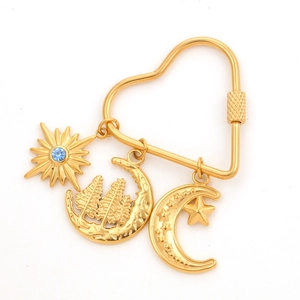 Detail of heart-shaped gold clasp with sun and moon celestial pendants and blue crystal
