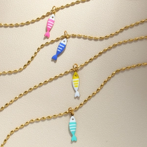Detail of gold beaded chain necklace with colorful enamel fish charms in macro view