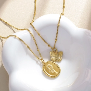 Dettaglio della collana con fiocco dorato e ciondolo girasole su piatto bianco