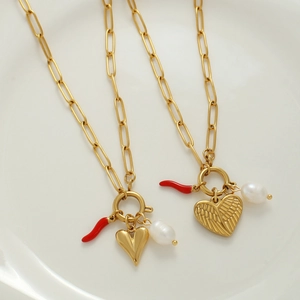 Dettaglio della collana a graffetta dorata con peperoncino rosso, perla e cuori