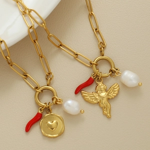 Collana a catena con charms angelo, cuore e perla su sfondo in pelle testurizzata
