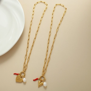 Dettaglio della collana a catena dorata con ciondolo a cuore e perla barocca