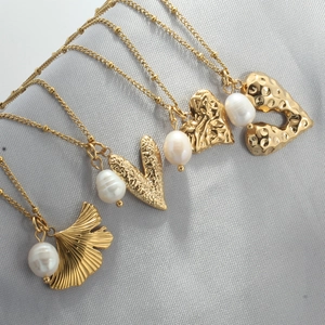 Detail view of gold heart pendants and baroque pearls on elegant grey silk fabric