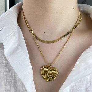 Gold double-layered necklace featuring a flat herringbone chain and a textured heart pendant