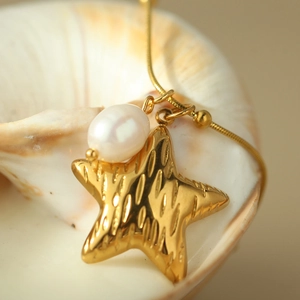 Collana con ciondolo a stella marina dorata e perla su una base a conchiglia