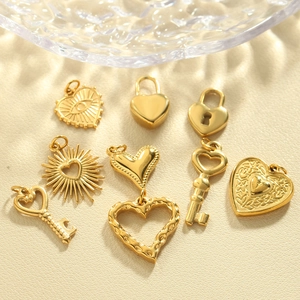 Vielzahl goldener Edelstahl-Herzanhänger und Charms auf elegantem cremefarbenem Hintergrund