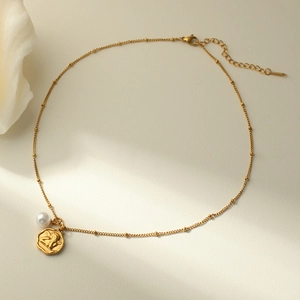 Détail d'une chaîne à billes dorée avec perle et pendentif médaille Cupidon