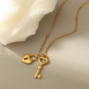 Gros plan détaillé du pendentif cadenas et clé en forme de cœur sur une chaîne à billes