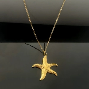Dettaglio ravvicinato di una collana con ciondolo a stella marina dorata satinata