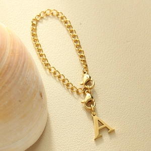 Macro detail of golden letter A pendant with Cuban chain and dual lobster clasps
