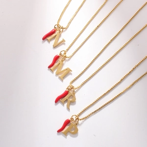 Detail of 18k gold plated box chains with red enamel chili and gold initial pendants
