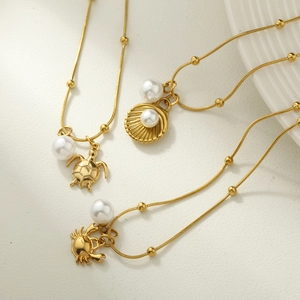 Macro detail of gold sea life pendants with pearls and beaded snake chains