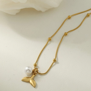 Detail of gold-plated fishtail pendant with white pearl on a delicate snake chain necklace
