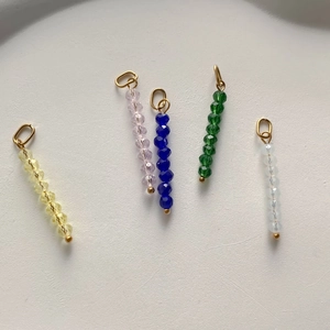 Detail of colorful faceted crystal bead pendants with golden metal loops for DIY jewelry
