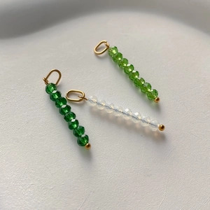 Three long beaded pendants in green and iridescent tones with golden metal loops