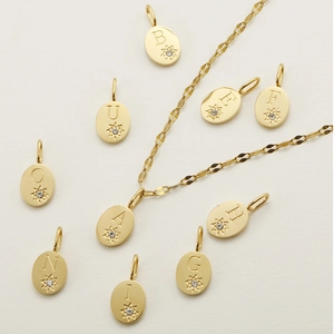Pendaglio ovale con lettera dorata, design a stella e piccoli cristalli