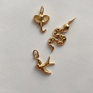 Detailed view of polished gold stainless steel elephant, snake and bird animal charms