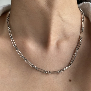 Détail d'un collier chaîne en or 18 carats avec des maillons texturés portés au cou