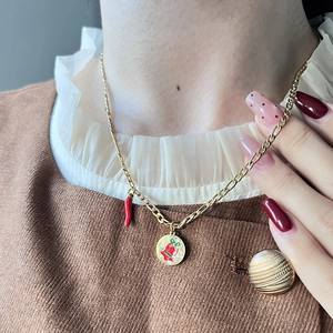 Festliche goldene Kette mit Paprika- und Glockenanhängern auf einem Model