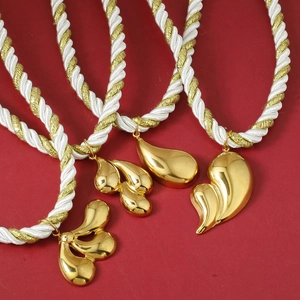 Modern gold floral pendant necklace with twisted rope chain on red texture background
