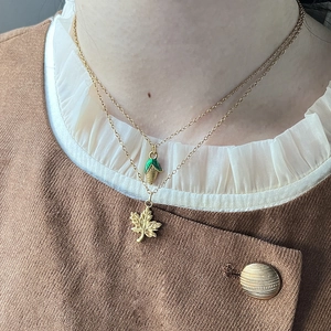 Layered gold necklaces with 3D corn and maple leaf pendants on a female model