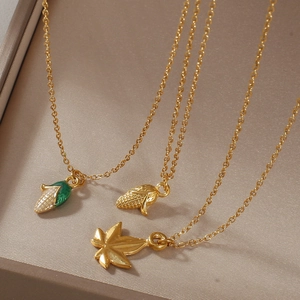 Detailed view of three gold-plated corn and maple leaf pendants in a jewelry box
