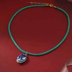 Retro ketting met keramische hanger met blauw bloemenpatroon en groen gevlochten koord