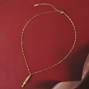 Collar de acero inoxidable dorado con colgante de pez y cadena de textura fina sobre fondo rojo
