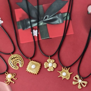Set de collares con colgante de flor y perla dorada con cordones negros en fondo festivo