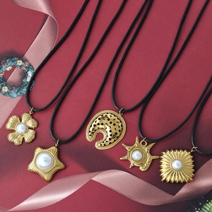 Collares con colgantes de perlas doradas y cordones negros sobre fondo rojo festivo