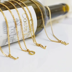 Golden Cuban chain necklace set with LOVE letter pendants on dark glass bottle